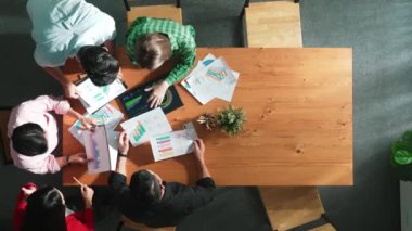Akıllı iş adamlarının yukarıdan görünüşü toplantıda verileri analiz eder. Birlikte çalışan bir grup iş adamı ve toplantı masasına yerleştirilen tabletin mali tablosuna bakıyorlar. Cemaat.