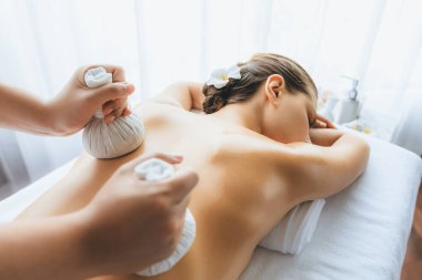 Sıcak bitkisel top spa masaj vücut tedavisi, masör kadın vücuduna nazikçe şifalı bitki torbası bastırıyor. Aromaterapi dinlenme sükuneti ve sükuneti kaplıca salonundaki atmosferi aydınlatıyor. Sessiz.