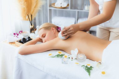 Sıcak bitkisel top spa masaj vücut tedavisi, masör kadın vücuduna nazikçe şifalı bitki torbası bastırıyor. Aromaterapi dinlenme sükuneti ve sükuneti kaplıca salonundaki atmosferi aydınlatıyor. Sessiz.