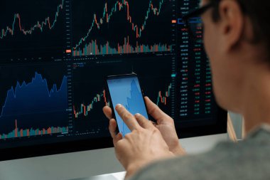 Akıllı borsa yatırımcıları ekranda akıllı telefon ile piyasa borsasını işaret ederek dizüstü bilgisayarın yanı sıra en yüksek dinamik yatırım oranını göstererek, modern işyerindeki veri planlamasına odaklanıyorlar. Bireysel.