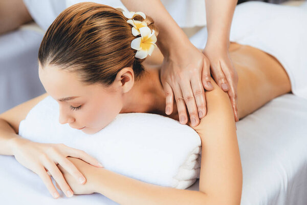 Caucasian couple customer enjoying relaxing anti-stress spa massage and pampering with beauty skin recreation leisure in day light ambient salon spa at luxury resort or hotel. Quiescent