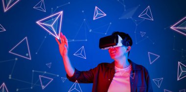 Heyecanlı, rahat gömlekli, mavi arka planda duran ve süzülen şekilli bir adam. Mutlu oyuncu metaevrene giriş yapıyor ve görsel gerçeklik dünyasına giriyor. Teknoloji yeniliği. Yaratıcılık.