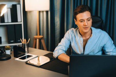 Akıllı iş adamı, gece vakti mavi perde arkasında iş hedefi olan finansal teknoloji veri raporlarını analiz etmek için veritabanı stoklarını araştırmak üzere dizüstü bilgisayarda uzaktan çalışıyor. Bireysel.