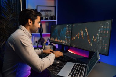 Akıllı tüccar işadamı, karanlık oda gecesinde neon ışıklı ofisteki arama pazarında yüksek kârla ekranda bilgisayar ve bilgisayar üzerinde dinamik borsa yatırımları üzerinde yoğunlaşıyor. Tahmin et..