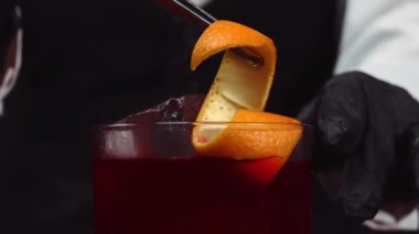Makrografi, Negroni kokteyli servis eden yetenekli bir barmenin elleri, siyah arka planlı canlı taze portakal dilimleriyle süslenmiş. Her yakın çekim kokteyl hazırlığını yakalar. Geliştirilebilir.
