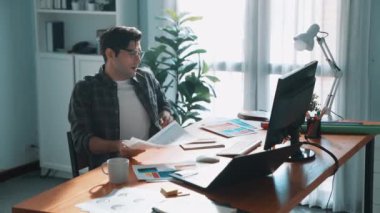 İç mimar dizüstü bilgisayarı, bilgisayarı ve kâğıdı olan toplantı masasında palete bakarken dizüstü bilgisayara bakıyor ve renk tasarlıyor. Renk tasarımı üzerinde çalışan iş adamına yakın çekim. Sempozyum.