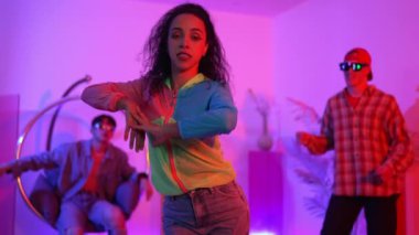 İspanyol hipster renkli kıyafetler giyer ve serbest stil müziğe el sallar. Profesyonel break dansçı neon ışıklarıyla ve modern stüdyo arkadaşlarıyla coşkuyla dans ediyor. Mutluluk.