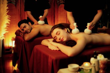 Sıcak bitkisel top spa masaj vücut tedavisi, masör nazikçe bitki torbasını çift müşteri vücuduna bastırıyor. Aromaterapi salonda mumların sıcacık ışığında dinlenme sükuneti. Sessiz.