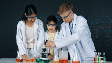 Zeki kız deney yapmak için heyecanlanan çeşitli öğrenciler iken beher kabına renkli solüsyon döker. Profesyonel bilim adamı kimyasal teoriyle kara tahtada deney yapmaya hazırlanıyor. Öğretim.