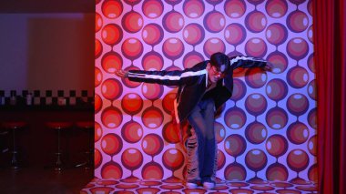 Asyalı break dansçı serbest stile geçiyor ve balon arka planlı kameraya bakıyor. Profesyonel hippi gündelik kıyafet giyer ve gözlük takar. Mutluluk.