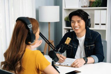 Gülümseyen radyo etkili sunucusu kulaklık takıyor kadın konuşmacı ile röportaj yapıyor sosyal medya internet sitesinden dinleyicilere bilgi paylaşıyor stüdyo kaydında sabah canlı yayın kanalı. İnfobahn.