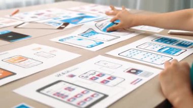 Mobil uygulama için kullanıcı arayüzü prototipi ya da masadaki program modeliyle birlikte web sitesi planlaması yapan bir şirket çalışanı. UX UI tasarımcısı kullanıcı dostu arayüz planını dikkate alır. Sinerjik