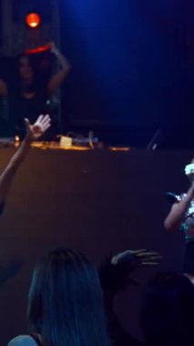 Bir grup insan disko gece kulübünde DJ 'in sahnede çaldığı müzikle dans ediyor. Yeni yıl partisi ve gece hayatı konsepti .