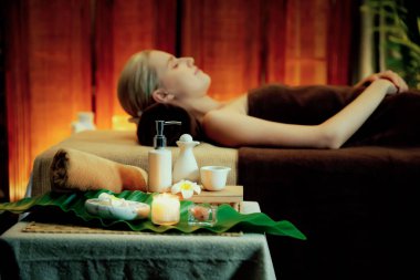 Aromaterapi masajı ambiyansı ya da spa salonu kompozisyon düzeneği bulanık kadınlara odaklı dekor mumları ve spa aksesuarları ile tatil köyü veya otel arka planında keyifli aroma spa masajı yapan. Sessiz.
