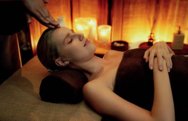 Beyaz kadın stres önleyici kafa masajı yapmaktan ve lüks otel veya otelde sıcak mum ışığında yüz güzelliği eğlencesi yapmaktan zevk alıyor. Sessiz.