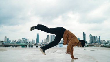 Profesyonel sokak dansçısının şehir manzaralı çatı katındaki dansçısının B-boy dans gösterisi. Çekici Asyalı hipster enerjik adımlar atıyor. Açık hava sporu 2024. Hiphop.