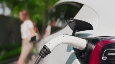 Yavaş çekim odaklı EV elektrikli araba yeşil sürdürülebilir şehir açık hava bahçesinde şarj çift bulanık arka planı şehir elektrikli araç iç organları için temiz şarj edilebilir
