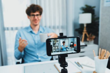 Etkilendiricinin sunucu kanalı akıllı telefon odaklı görüntüde kahve fincanı tanıtımını sunuyor. Sosyal medyada geçmişi bulanık ve modern ofis evinde rahatlama süresi olan bir adam geçmişi var. Toplayıcı.