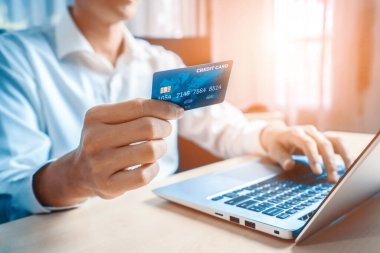 Genç adam, laptop bilgisayar başvurusu ya da web sitesinde online alışveriş yapmak için kredi kartı kullanıyor. E-ticaret ve online alışveriş konsepti. uds