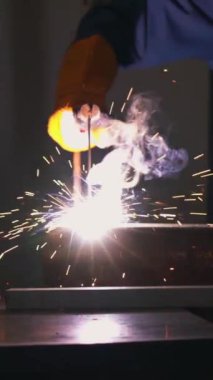 Fabrikada çelik kaynak makinesiyle çalışan metal kaynakçı güvenlik ekipmanı takıyor. El becerisi iş gücü kavramına göre metal imalatı ve inşaat bakım hizmeti.