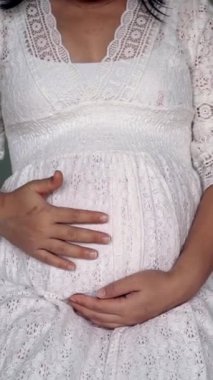 Hamile bir kadın çocuğuna bakarken kendini mutlu hissediyor. Hamile karnında bebek taşıyan hamile bir anne. Doğum öncesi bakım ve kadın hamileliği konsepti.