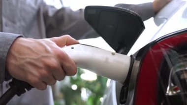 Yavaş çekim çift yazın yeşil sürdürülebilir şehir açık bahçesinde elektrikli araba şarj ile seyahat elektrikli aracın temiz yeniden şarj edilebilir enerjisi için kentsel sürdürülebilirlik yaşam tarzı olarak