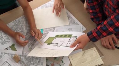 Mimari döküman, ölçüm araçları ve ahşap blokların modern ofiste etrafa saçıldığı masa üzerine planlar yapma konusunda akıllı mimar ve güvenlik mühendisi tartışması. - Yakın çekim. Tanımlama.