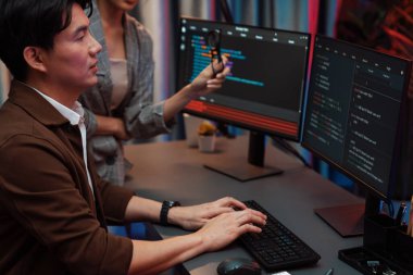 Bilgi teknolojisi geliştiricileri modern ofisteki neon ışık odasında verileri çevrimiçi olarak çalıştıran akıllı web sitesi geliştirme kodlayıcı sistemine işaret ediyorlar. İnfobahn.