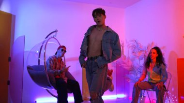 Çok kültürlü bir arkadaş kürsüde otururken Asyalı yetenekli bir dansçı modern müziğe geçiyor. Profesyonel dansçı, hipster takımı tezahürat yaparken ve desteklerken enerjik adımlar atıyor. Mutluluk.