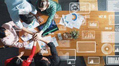 Başarılı bir projeyi kutlamak ya da satışları artırmak için toplanan akıllı takım görüşü. Çeşitli insanların yatırım istatistikleriyle el ele tutuşmalarının havadan görüntüsü. Cemaat.