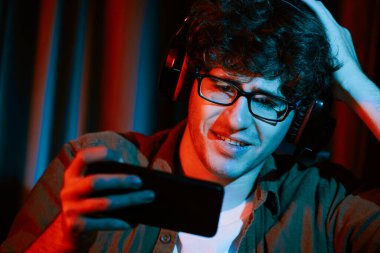 Stresli genç oyun flaması takımı akıllı telefondan Esport 'la oynuyor. Daha sert oyun seviyesinde, neon ışıklı odada kazanmanın utancı ve şaşkınlığı ile mücadele ediyorlar. Strateji planı uyguluyorum. Toplayıcı.