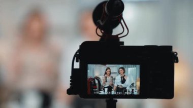 Arka görünüm, kamera ekranının arkasında iki kadın nüfuzlu görüntüleyicinin video görüntülerini, video görüntülerini, kıyafetleri, sosyal medyayı ya da blogu görüntülemesini gizler. Canlı yayın için stüdyo ışıklandırmalı kızlar canlı yayın pazarlama kayıt oturumu