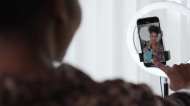 Arkadan bakıldığında kadın nüfuzlu kişi canlı yayın vlog görüntülerini çeker. Önemli sosyal medya ya da blogu gizler. Stüdyo ışıklandırmalı bir kız çevrimiçi pazarlama oturumu yayını için.