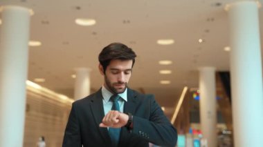 Kafkasyalı zeki iş adamı iş arkadaşını beklerken saate bakıyor. Bulanık geçmişiyle alışveriş merkezinde dikilirken yönetici takım elbise giyiyor. Yatırımcı mavi takım elbise giyer. Sevinçli..