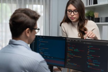 Masada çalışan erkek programcının karşısında duran kadın meslektaşım iki bilgisayar ekranında kodlama web sitesi yazılım sistemi projesini tartışmak için tam yığın veri dizaynı ile karşılaştırıyor. Varsayım.