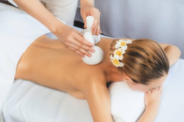 Sıcak bitkisel top spa masaj vücut tedavisi, masör kadın vücuduna nazikçe şifalı bitki torbası bastırıyor. Aromaterapi dinlenme sükuneti ve sükuneti kaplıca salonundaki atmosferi aydınlatıyor. Sessiz.