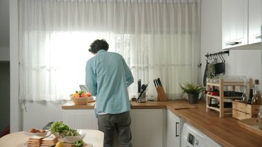 Mutlu baba yemek pişirirken müziğe geçiyor ve modern mutfakta öğle yemeği hazırlıyor. Aktif baba, sebze ve mutfak gereçleri ile çevrili sağlıklı yemek ya da salata yaparken şarkıyla dans ediyor. Pedagoji.