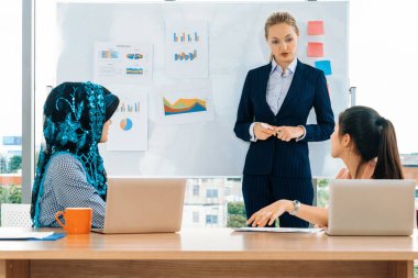 Çok kültürlü çalışma grubu. Farklı etnik kökenden iş kadınları, Kafkasyalı, Asyalı ve Araplardan oluşan bir ekip ofiste dizüstü bilgisayarla birlikte çalışıyor. Çok ırklı takım çalışması konsepti. uds