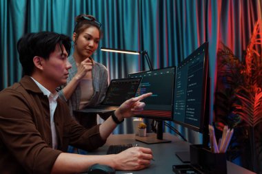 Modern ofisteki neon ışık odasında bilgi ağını gösteren dizüstü bilgisayarla iki ekranda veri çalıştıran akıllı web sitesi geliştirme kodlayıcı sistemini tartışan IT geliştiricilerinin ciddiyeti. İnfobahn.