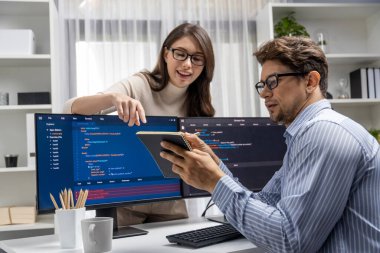 Masada çalışan erkek programcının karşısında duran kadın meslektaşım iki bilgisayar ekranında kodlama web sitesi yazılım sistemi projesini tartışmak için tam yığın veri dizaynı ile karşılaştırıyor. Varsayım.