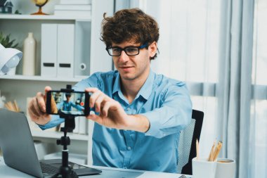 Etkilendiricinin sunucu kanalı akıllı telefon görüntüsünü bulanıklaştırıyor, ekipman kaydı hazırlamak için çevrimiçi yayın yapıyor, modern merkez ofisteki sosyal medyada portre arka planına odaklanıyor. Toplayıcı.