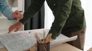 Mimari döküman, ölçüm araçları ve ahşap blokların modern ofiste etrafa saçıldığı masa üzerine planlar yapma konusunda akıllı mimar ve güvenlik mühendisi tartışması. - Yakın çekim. Tanımlama.