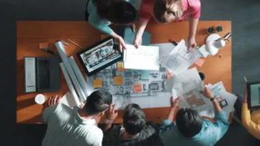 Planı elinde tutan inşaat mühendisi ekibinin en iyi görüntüsü ve dizüstü bilgisayar, proje planı ve planıyla masada duruyor. Yapışkan notları planlayan ve yazan yetenekli proje yöneticisinin havadan görünüşü. Sempozyum.