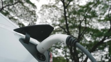 Green City Park 'taki otoparkta yavaş çekim EV elektrikli araba şarj bataryası. Sürdürülebilir ve çevre dostu şehir yolculuğu için yenilenebilir otomobil için alternatif temiz enerji teknolojisi. Yararlı