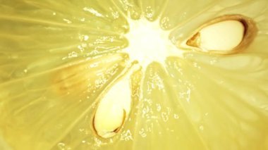 Dilimlenmiş taze limonun makro fotoğrafı canlı sarı renkte ve narenciye meyvesinin sulu etinden görülebilir. Limonun eti dolgun görünüyor, sulu olduğunu ima ediyor. Geliştirilebilir