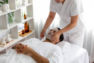 Kaplıca salonunun sakin, modern gündüz atmosferi. Kadın müşteri yüz maskesi takarak kendini yenilemeye çalışıyor. Yüz bakımı ve güzellik kozmetolojisi prosedürü. Sessiz.