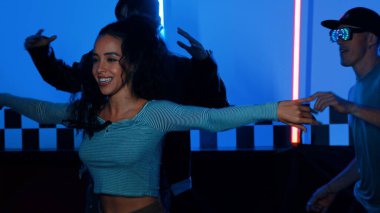 Gündelik gömlekli, gözlüklü, neon ışıkla dans eden farklı insanlar. Gece kulübünde dans ederken kameraya bakıp sokak dansı yapan çok kültürlü break dansçı. Mutluluk.