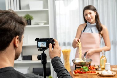 Kameraman, şef etkisinde olan kadına makarna pişiren, domates soslu spagetti hazırlayan, içerik tarifini saran, modern stüdyoda özel sağlıklı yemekler sunan bir kayıt yapıyor. Varsayım.