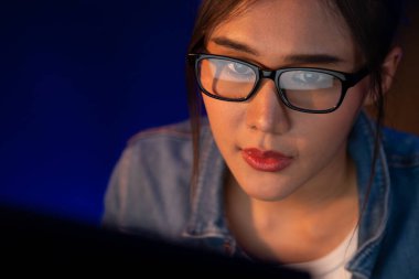 Ciddi yüzlü genç Asyalı gözlüklü genç bir portre internette proje yaratıcısı sosyal medyayı aramak için bilgisayara bakıyor, geceleri neon modern ofiste strateji yaratıcısı planlıyorlar. Taktik.