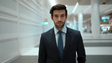 Beyaz arkaplan ile alışveriş merkezinde dikilirken kameraya bakan gülümseyen iş adamı. İş elbisesi giyerken kameraya gülümseyen başarılı adamın yakın çekimi. Mutlu yönetici kameraya bak. Sevinçli..